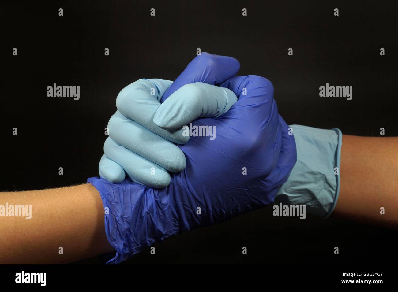 Symbol der Coronavirus-Pandemie. Handshake durch Gummihandschuhe geschützt. Stockfoto