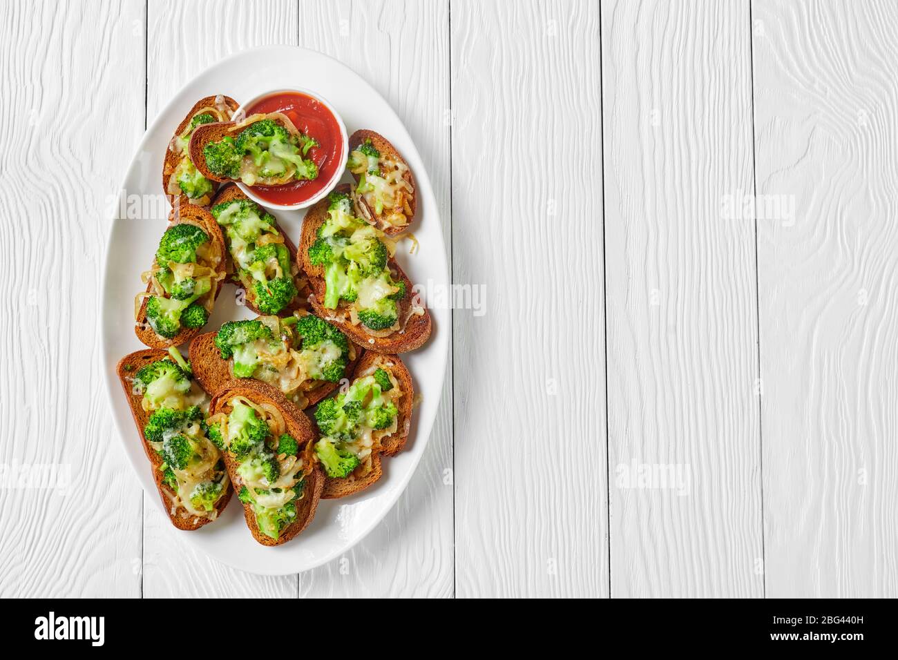 Brokkoli schmilzt offene vegane Sandwiches mit geröstetem Brokkoli und gebratener Zwiebel mit geschmolzenem Provolonkäse auf einem weißen Teller auf einem Stockfoto