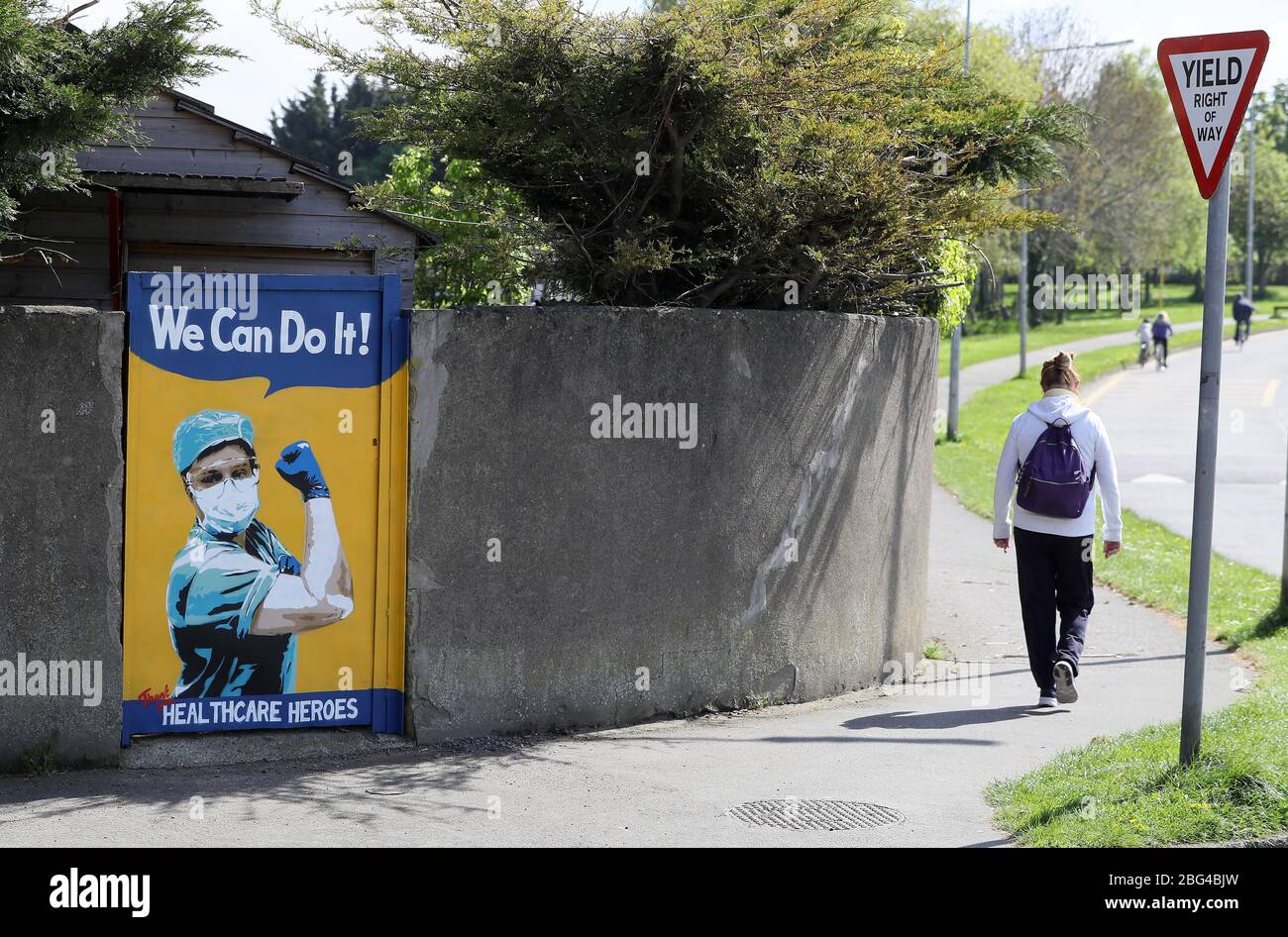 Eine Frau geht an einem Tor in Süd-Dublin an einem Wandgemälde der irischen Künstlerin Emmalene Blake vorbei und dankt den Gesundheitsarbeitern für ihre Arbeit während der Coronavirus-Pandemie. Der Dubliner Künstler hat eine Serie von Wandmalereien geschaffen, um Menschen dazu zu ermutigen, sich an soziale Distanzierungsregeln zu halten, die Künstler wie Dua Lipa, Robyn und Cardi B. zeigen Stockfoto