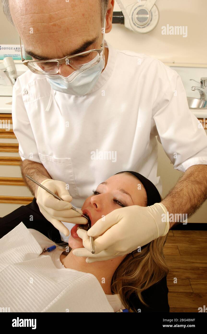 Ein Zahnarzt verwendet eine zahnärztliche holen um die Weichteile Prüfung seines Patienten zu unterstützen. Stockfoto