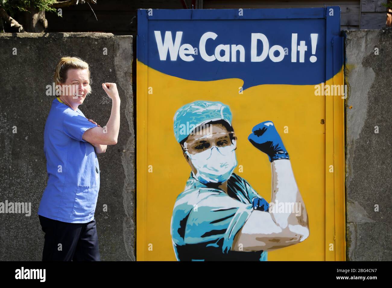 Michelle Farrell, eine Krankenpflegeassistentin am Junction House Primary Healthcare Center, posiert neben einem Wandgemälde der irischen Künstlerin Emmalene Blake an einem Tor in Süd-Dublin und dankt den Krankenpflegern für ihre Arbeit während der Coronavirus-Pandemie. Der Dubliner Künstler hat eine Serie von Wandmalereien geschaffen, um Menschen dazu zu ermutigen, sich an soziale Distanzierungsregeln zu halten, die Künstler wie Dua Lipa, Robyn und Cardi B. zeigen Stockfoto