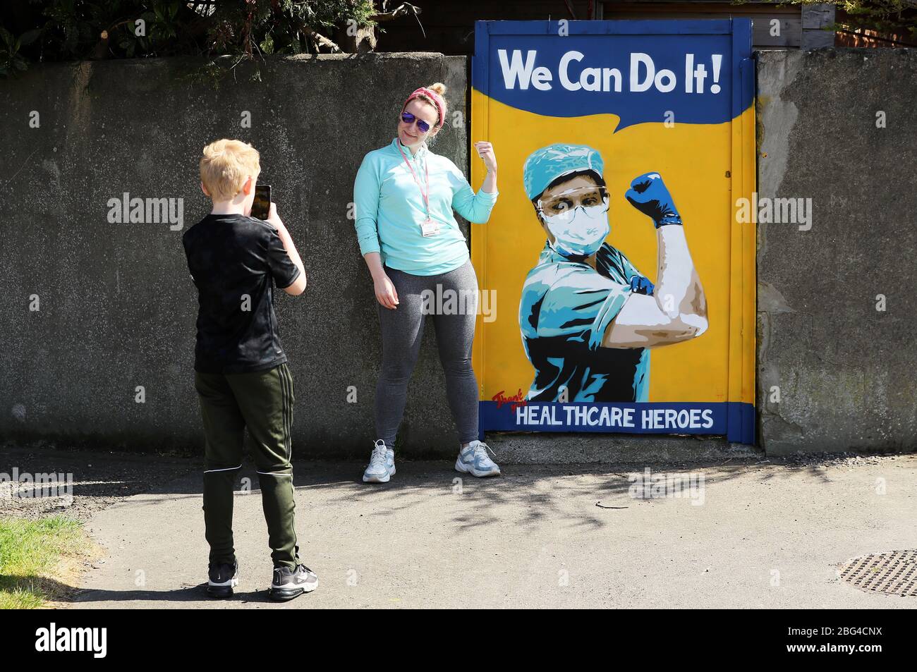 Shauna Murphy, eine Krebsspezialistin am St. James's Hospital, posiert neben einem Wandgemälde der irischen Künstlerin Emmalene Blake an einem Tor in Süd-Dublin und dankt den Gesundheitsfachkräften für ihre Arbeit während der Coronavirus-Pandemie. Der Dubliner Künstler hat eine Serie von Wandmalereien geschaffen, um Menschen dazu zu ermutigen, sich an soziale Distanzierungsregeln zu halten, die Künstler wie Dua Lipa, Robyn und Cardi B. zeigen Stockfoto