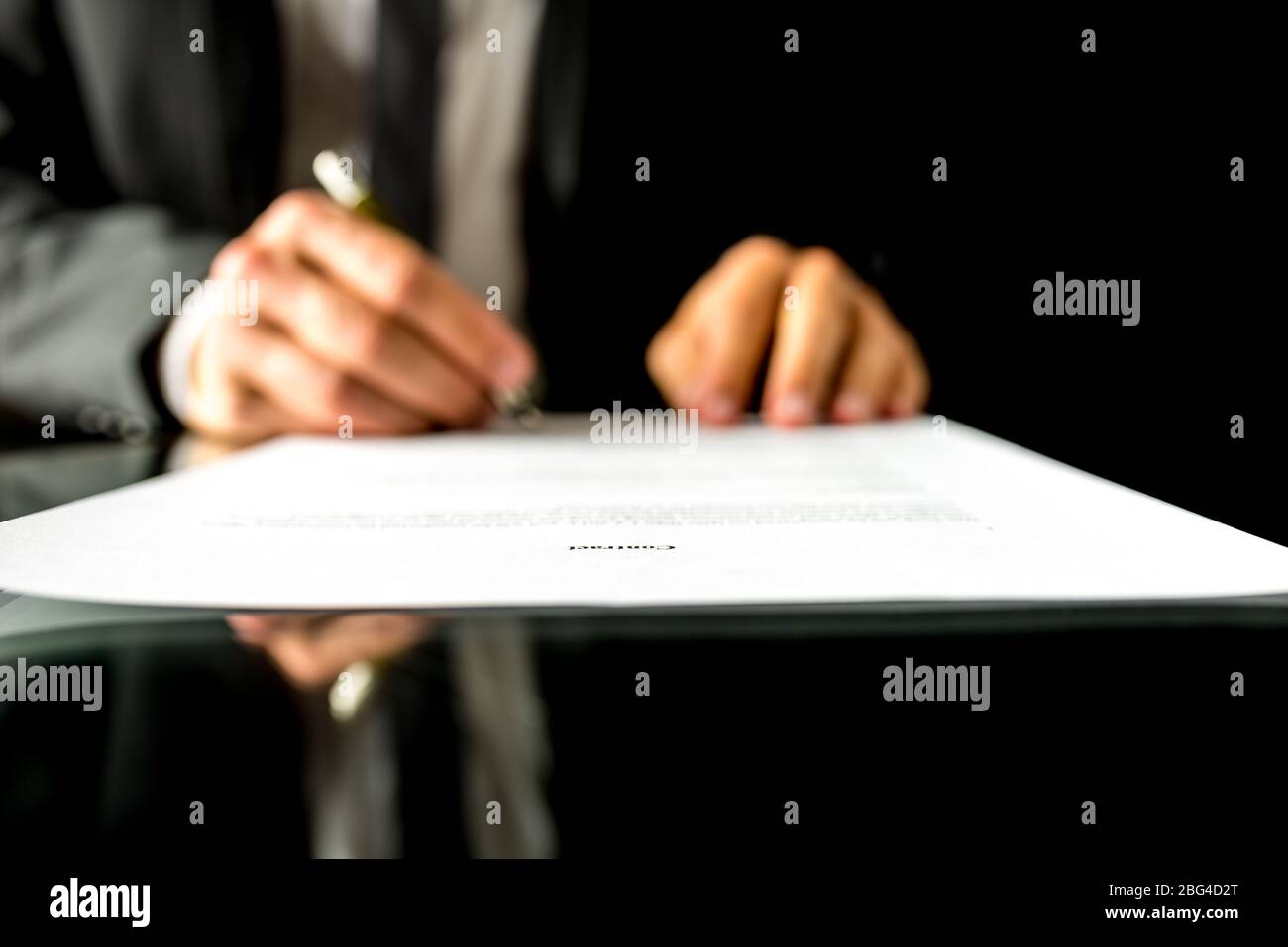 Nahaufnahme der verschwommenen Hände eines Geschäftsmannes, der ein Dokument oder einen Vertrag unterzeichnet, mit Fokus auf den Text Vertrag. Flache freiheitsgrade Stockfoto