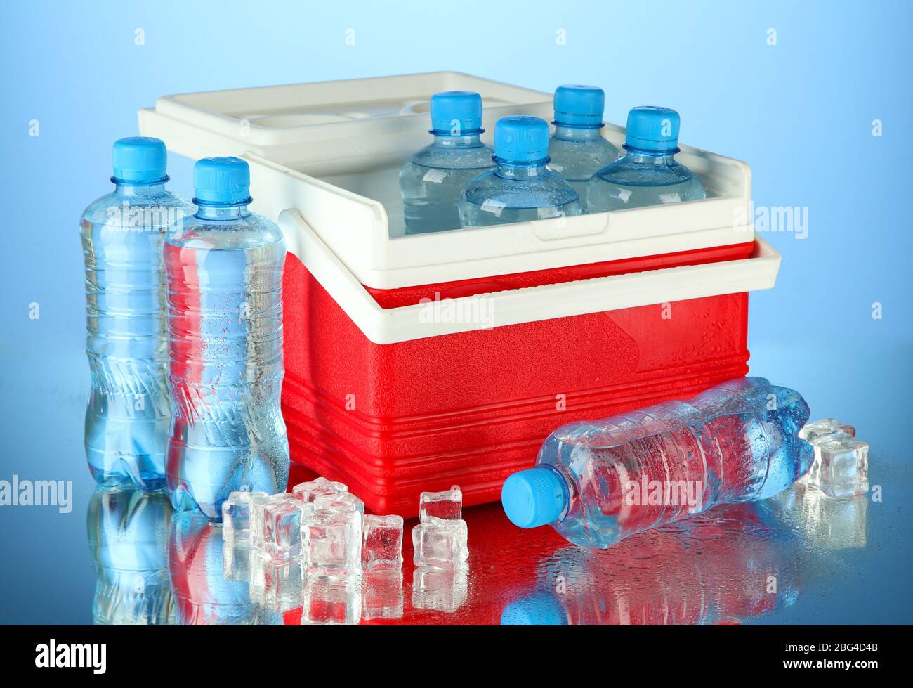 Reisekühlschrank mit Wasserflaschen und Eiswürfeln, auf blauem Hintergrund Stockfoto