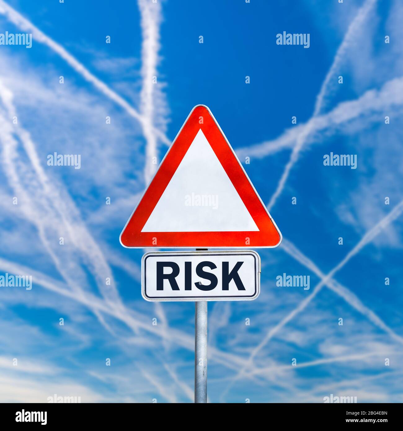 Dreieckige leere Straßenschild mit Wort Risiko in zusätzlichen Raum unten geschrieben. Über blauem Himmel mit sich kreuzenden Kondensstreifen. Stockfoto