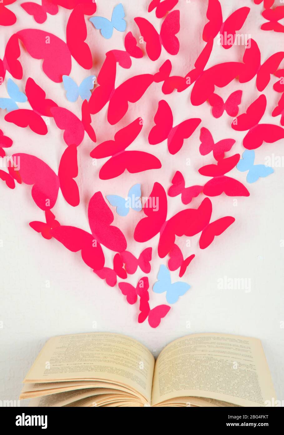Papierschmetterlinge in Form von Herz fliegen aus Buch Stockfoto