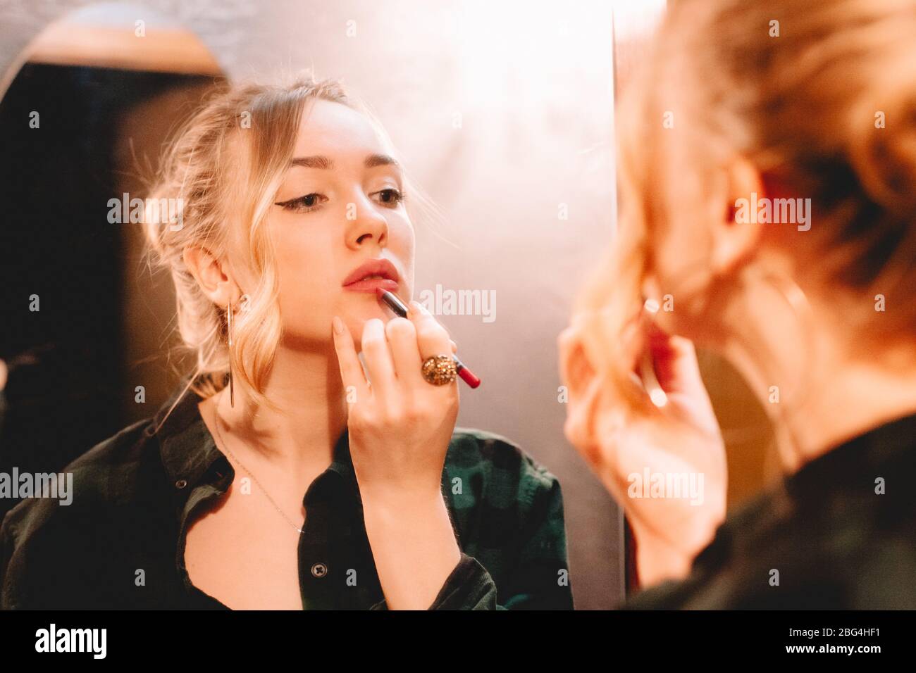 Junge Frau mit Lippenstift beim Zeichnen Konturen Anwendung Lippenstift tun Make-up zu Hause immer bereit zu gehen Stockfoto
