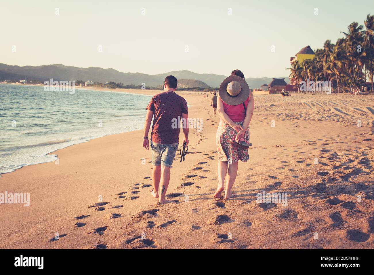 Mann und Frau, die am Strand bei Sonnenuntergang in Mexiko spazieren Stockfoto