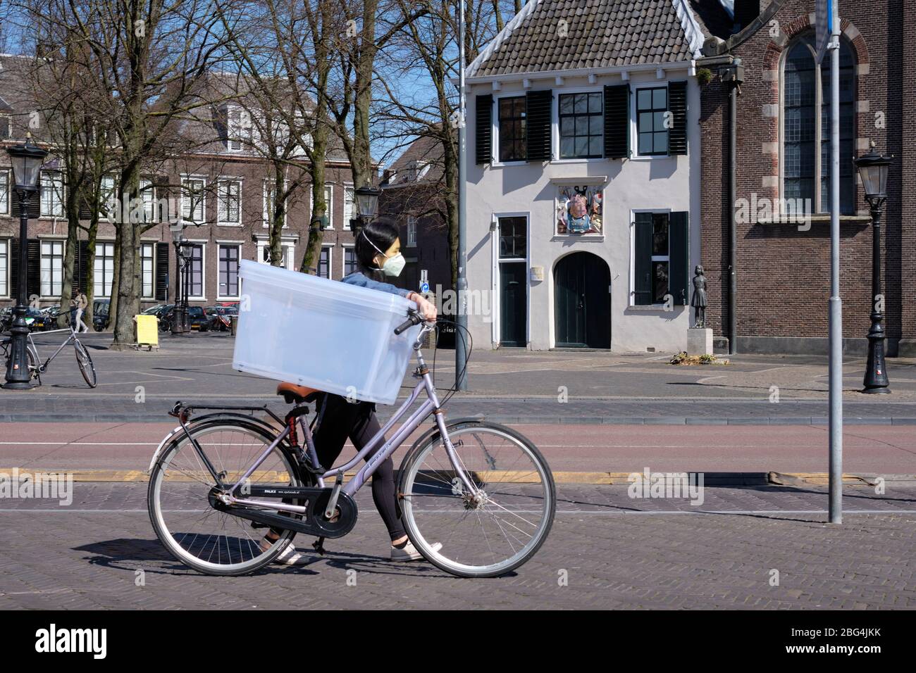Corona Crisis: Ein einsames Mädchen mit Gesichtsmaske im verlassenen historischen Zentrum von Utrecht, Niederlande. Der Blumenmarkt auf dem Platz ist geschlossen. Stockfoto