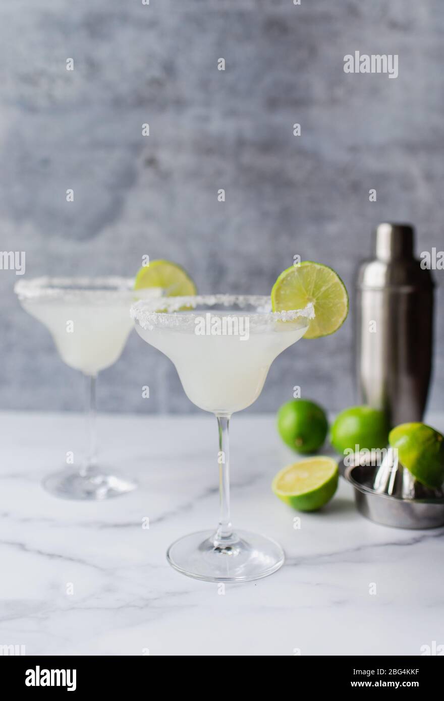 Zwei margarita-Cocktails mit Limetten und Shaker auf weißem Marmortisch Stockfoto