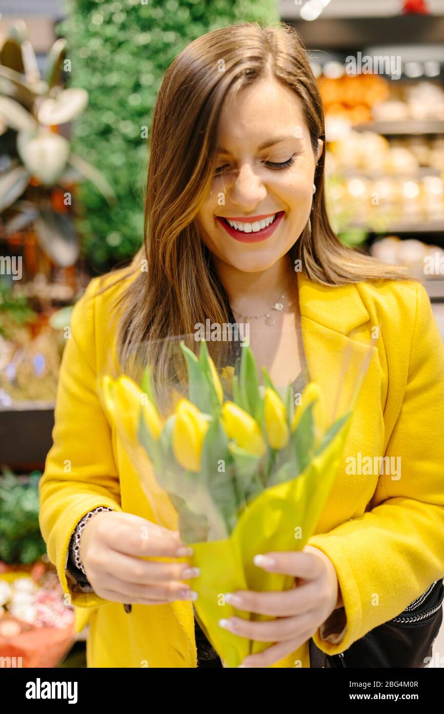 Junge Frau lachend mit einem Strauß gelber Tulpen. Sie erhält einfach Stockfoto
