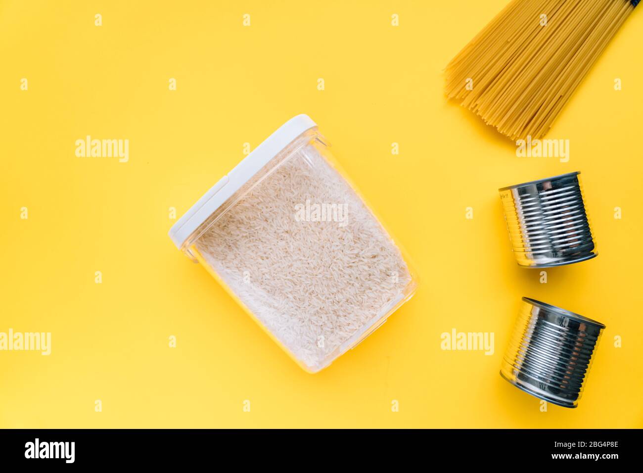 Lebensmittel-Lieferungen Krise Nahrungsmittelvorrat für Coronavirus Quarantäne Isolationsperiode in gelbem Hintergrund. Verschiedene Lebensmittel in Aluminiumdosen, Reis, Pasta. Essen d Stockfoto