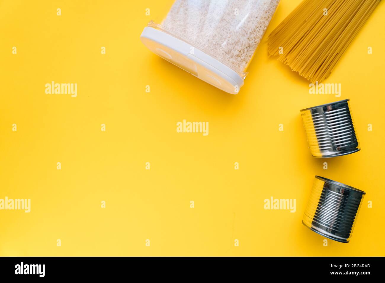 Lebensmittel-Lieferungen Krise Nahrungsmittelvorrat für Coronavirus Quarantäne Isolationsperiode in gelbem Hintergrund. Verschiedene Lebensmittel in Aluminiumdosen, Reis, Pasta. Essen d Stockfoto
