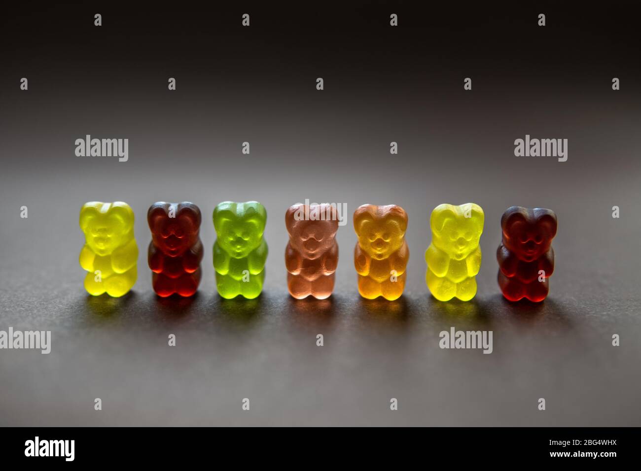 Sammlung von hintergrundbeleuchteten bunten Gummibärchen auf einem neutralen Hintergrund. Geringe Schärfentiefe. Stockfoto