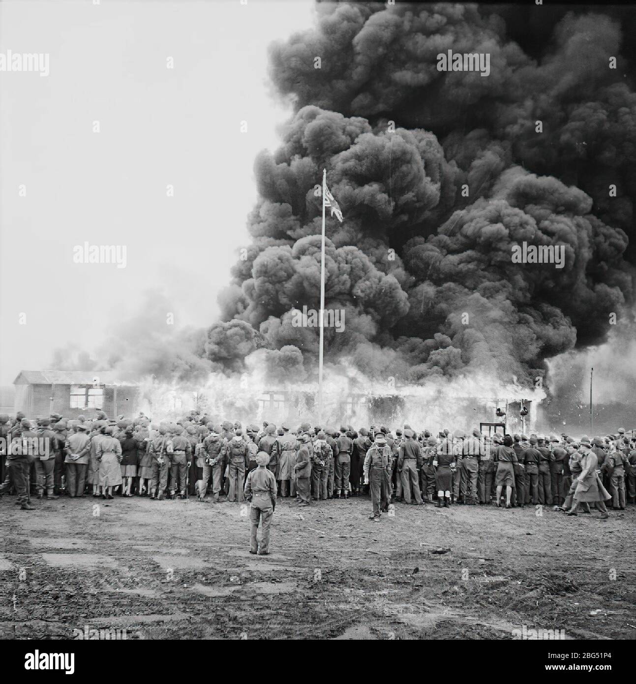 Dokumentation zum Zweiten Weltkrieg. Menschenmengen beobachten, wie britische Soldaten kurz nach ihrer Befreiung im April 1945 die letzte verbliebene Hütte des Konzentrationslagers Bergen-Belsen in Brand setzen Stockfoto