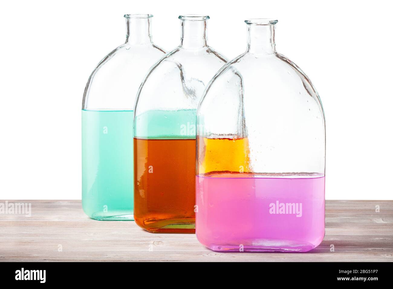 Glasflaschen mit farbigen Aquarelllösungen auf Holzplatte mit Aussparung Hintergrund Stockfoto