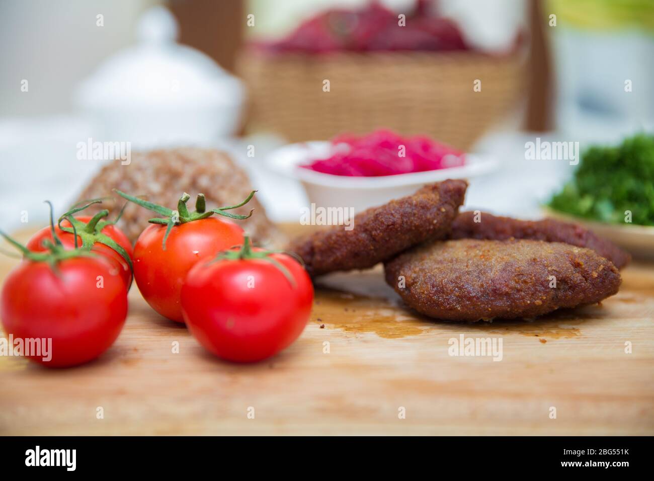 Fleischschnitzel, gebackener Buchweizen auf einem Holzbrett. Rotkohl-Sauerkraut . Knoblauch, Zwiebeln, Tomaten. Gehackter Koriander. Hausgemachte Koteletts mit Haferflocken Stockfoto