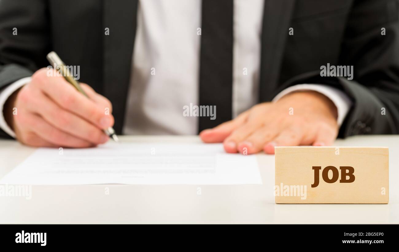 Nahaufnahme Job Text auf kleinen Holzstück in Front Geschäftsmann beim Schreiben auf weißen Tisch. Ein einfaches Jobkonzept. Stockfoto