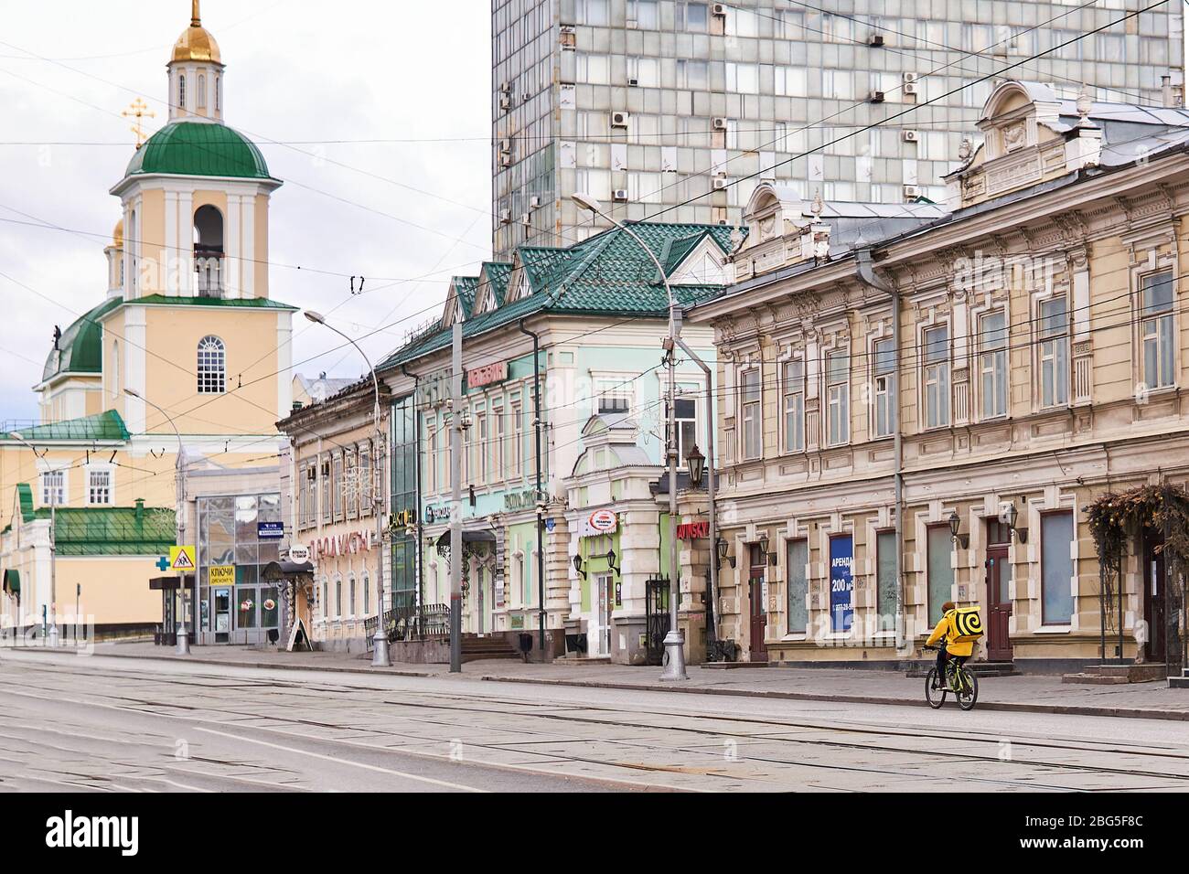 Perm, Russland - 19. April 2020: Der Kurier-Online-Lebensmittelzulieferdienst fährt während des Ausbruchs von COVID-19 ein Fahrrad auf einer leeren Straße Stockfoto