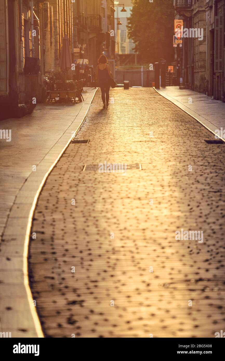 Frau, die bei Sonnenuntergang in Bordeaux, Frankreich, auf der Straße geht Stockfoto
