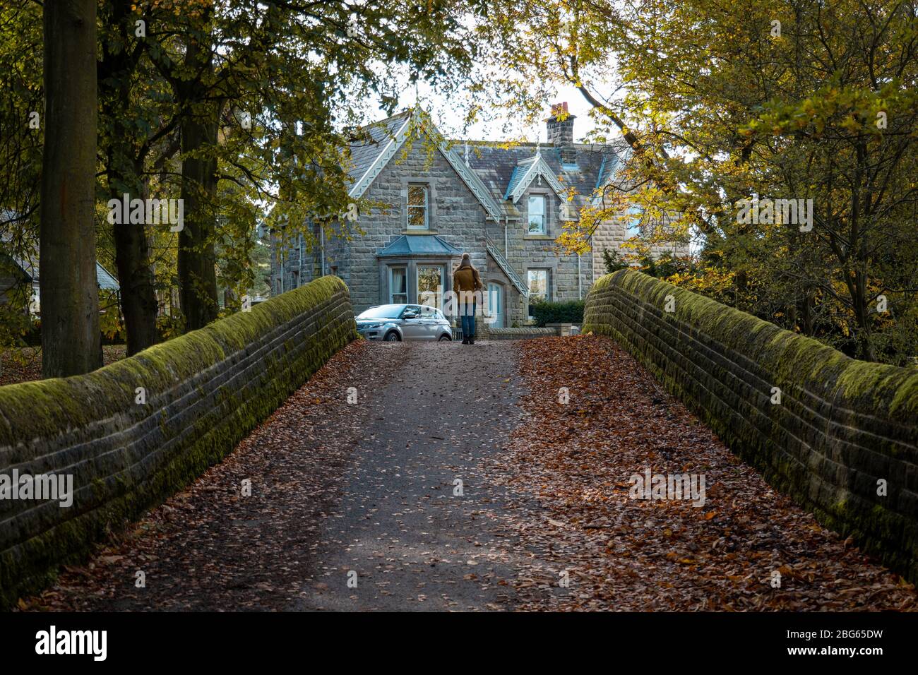 Eine junge attraktive Frau stand im Herbst auf einer alten Steinbrücke in der landschaft von yorkshire Stockfoto