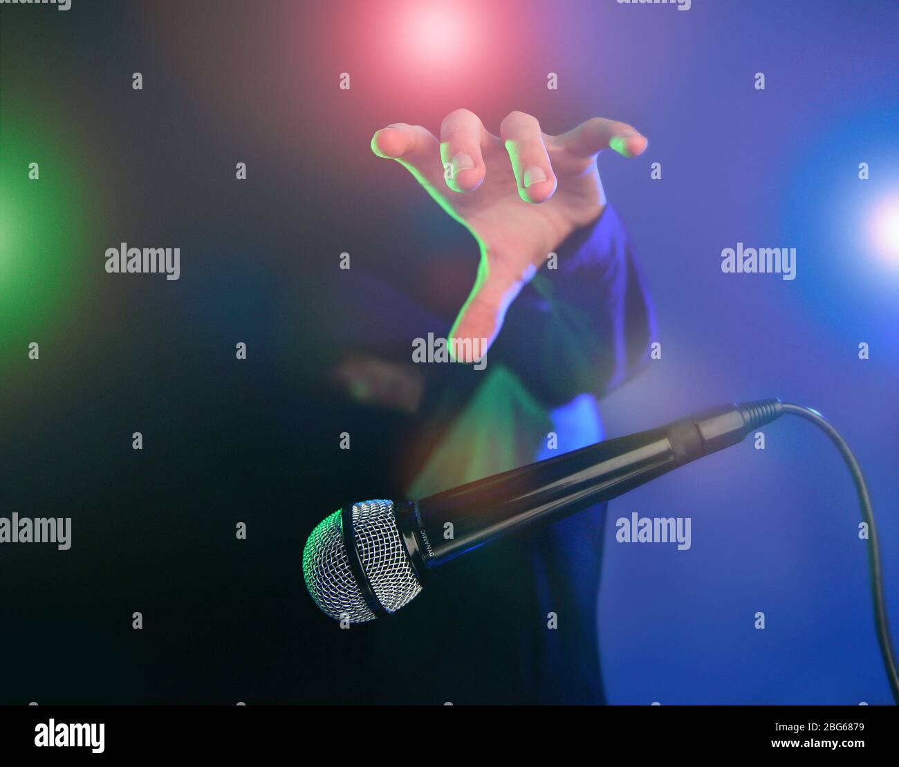 Bild des Mikrofonkonzepts ablegen. Aufgenommen mit Bühnenbeleuchtung, mehrfarbigem Effekt und coolem Kerl mit Hoodie. Stockfoto