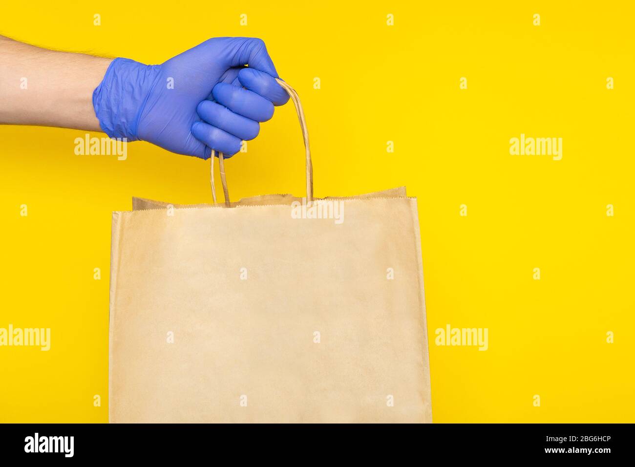 Lieferung Mann in medizinischen Handschuhen hält Papier Handtasche mit Lebensmittelbehältern, Lieferungen aus dem Lebensmittelgeschäft isoliert. Safe kontaktlosen Lieferservice, Stockfoto