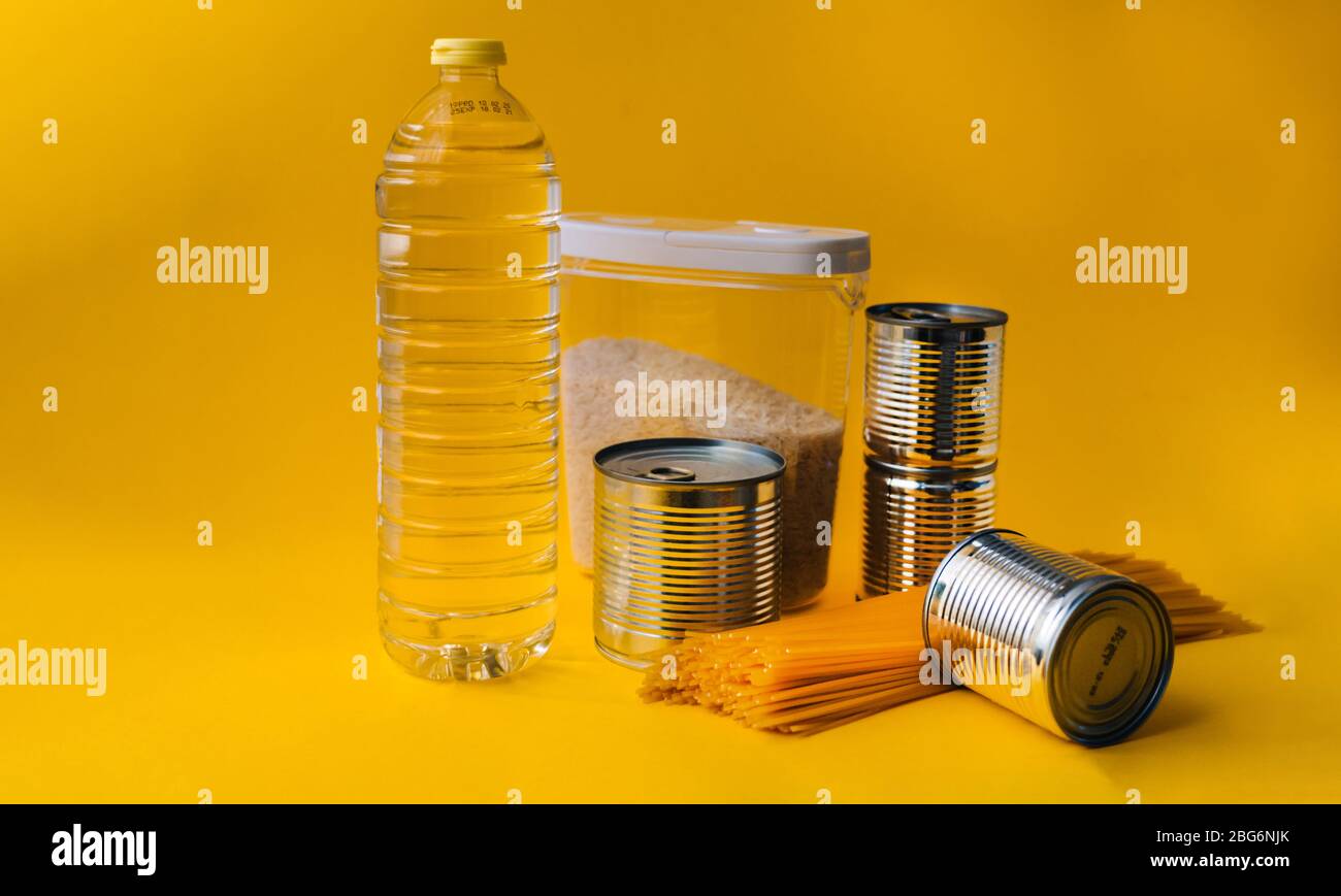 Lebensmittel-Lieferungen Krise Nahrungsmittelvorrat für Coronavirus Quarantäne Isolationsperiode in gelbem Hintergrund. Verschiedene Lebensmittel in Aluminiumdosen, Reis, Pasta. Essen d Stockfoto