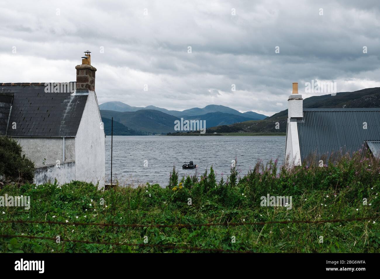 Blick nach Osten hinunter Loch Broom zwischen zwei kleinen traditionellen Hütten aus der kleinen Highland-Stadt Ullapool. Stockfoto