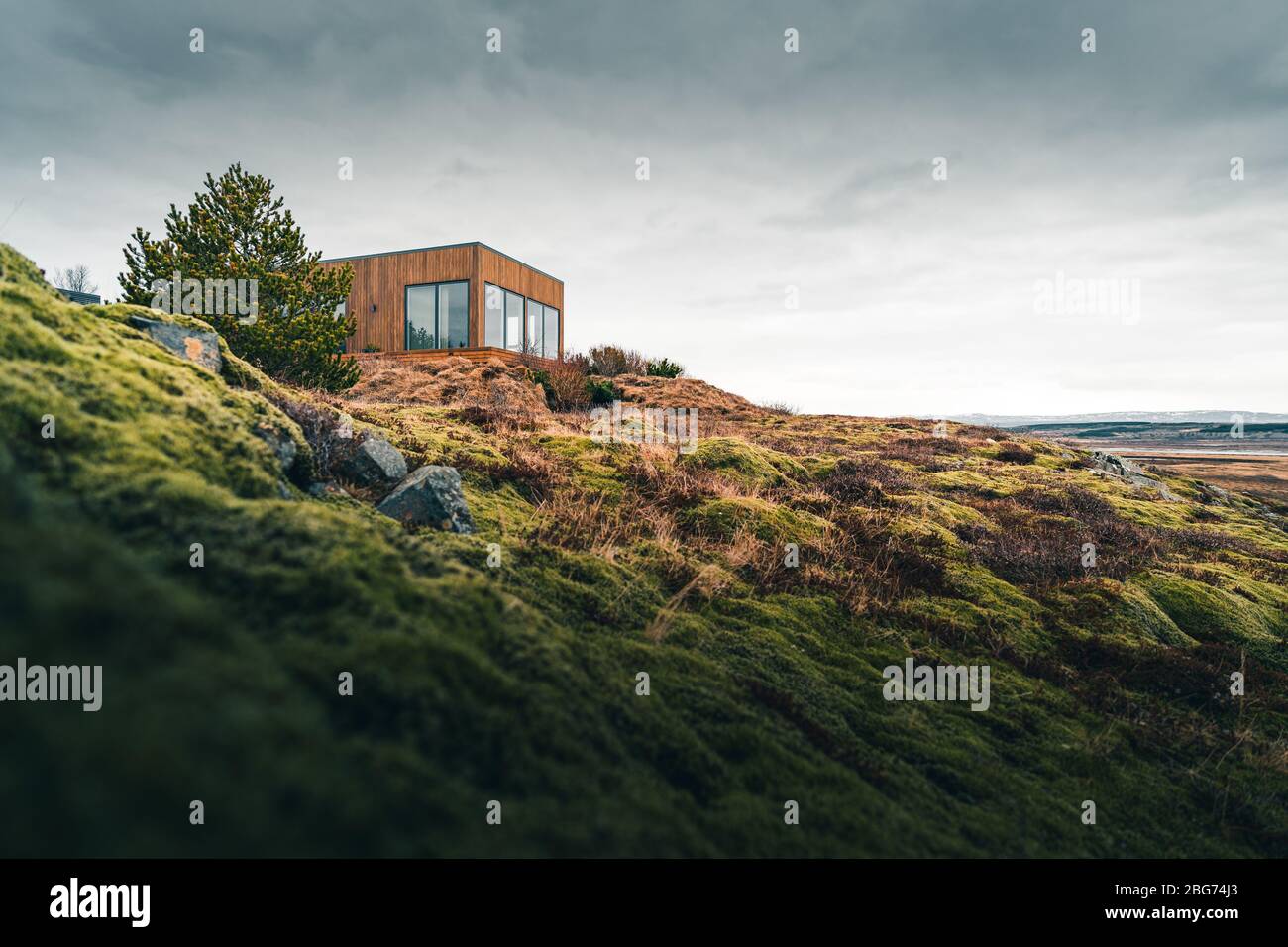 Ein winziges Haus auf einem grasbewachsenen Hügel, perfekt für einen isolierten Urlaub oder einfach nur einen ruhigen Urlaub in der Verbindung mit der Natur. Moderne Architektur in der Stockfoto