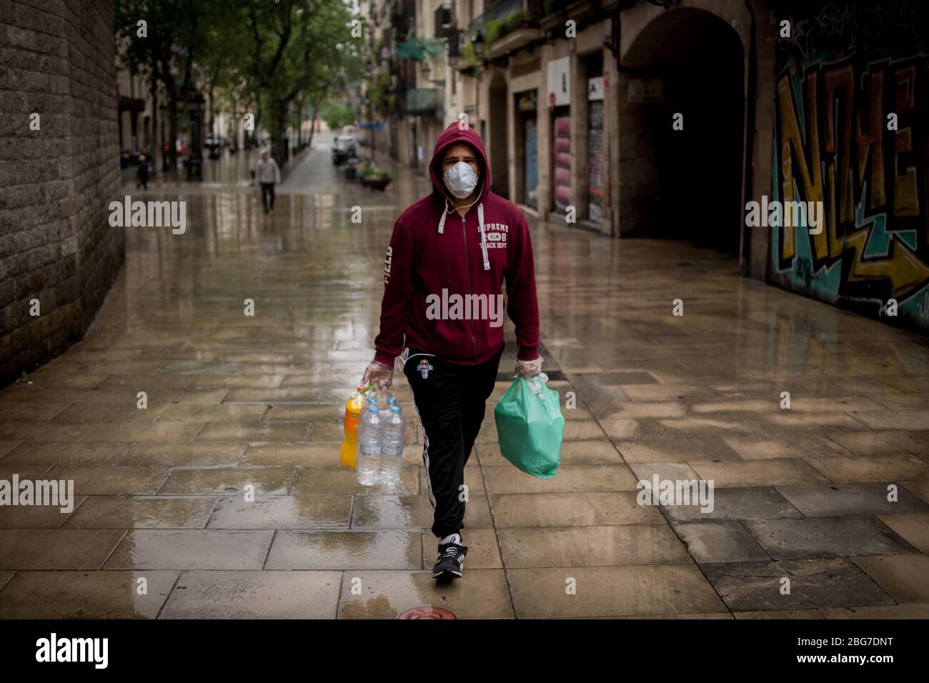 20. April 2020, Barcelona, Katalonien, Spanien - EIN Mann mit Gesichtsmaske geht unter dem Regen in Barcelona. Die Todesfälle durch das Coronavirus fallen in Spanien auf 399, während die bestätigten Fälle jetzt 200,000 übersteigen. Quelle: Jordi Boixareu/Alamy Live News Stockfoto