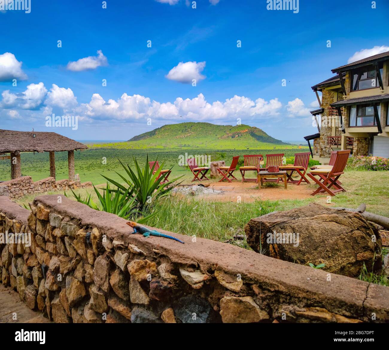 Kamin und Holzstühle. Im Hintergrund ist ein wunderbarer Blick auf den Tsavo East National Park in Kenia. Stockfoto
