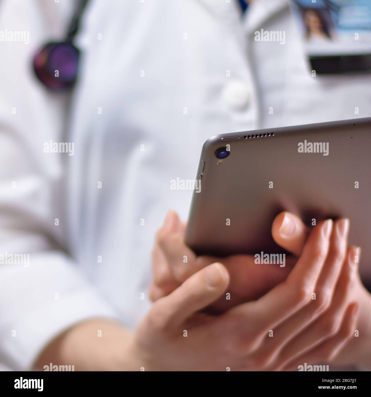 Tablet in den Händen von Gesundheitsexperten aus nächster Nähe. Weißes Fell, Stethoskop und Abzeichen im Hintergrund sichtbar. Hände eines Pflegefachpersonals oder PA U Stockfoto