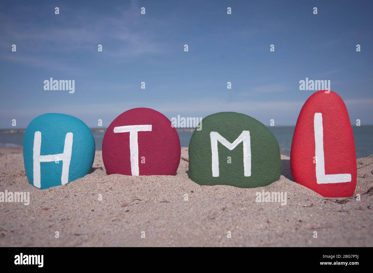 HTML, Hypertext Markup Sprache mit mehrfarbigen Steinbuchstaben am Strand Stockfoto