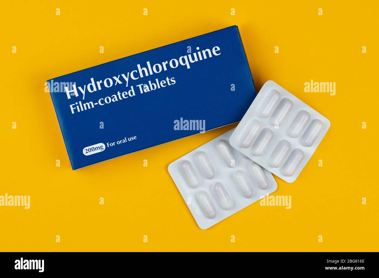 Eine Schachtel Tabletten mit der Aufschrift Hydroxychloroquin schoss vor gelbem Hintergrund. Stockfoto