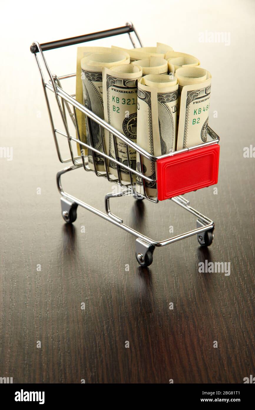 Einkaufswagen mit Dollar, auf dunklem Hintergrund Stockfoto