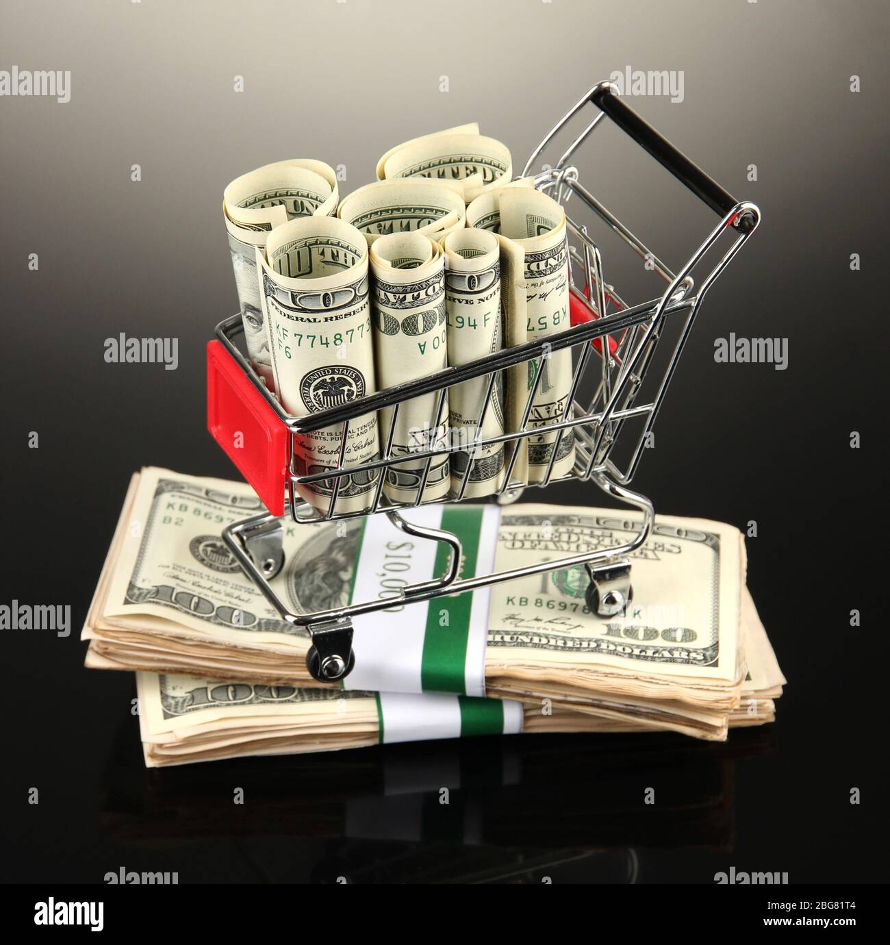 Einkaufswagen mit Dollar, auf dunklem Hintergrund Stockfoto