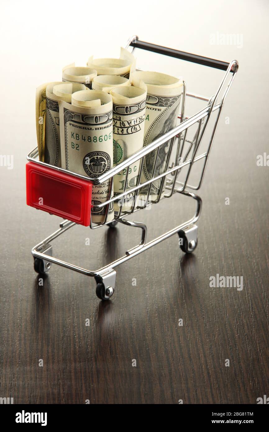 Einkaufswagen mit Dollar, auf dunklem Hintergrund Stockfoto