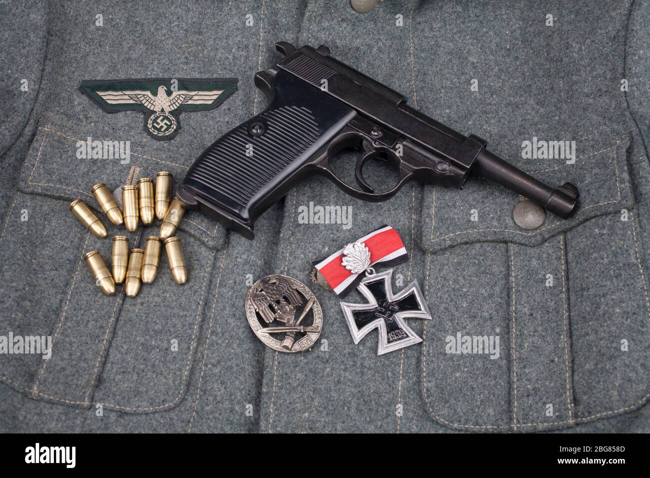 WWII Ära nazi deutsche Armee 9 mm halbautomatische Pistole mit Eisenkreuz Auszeichnung auf Armee grau einheitliche Hintergrund Stockfoto