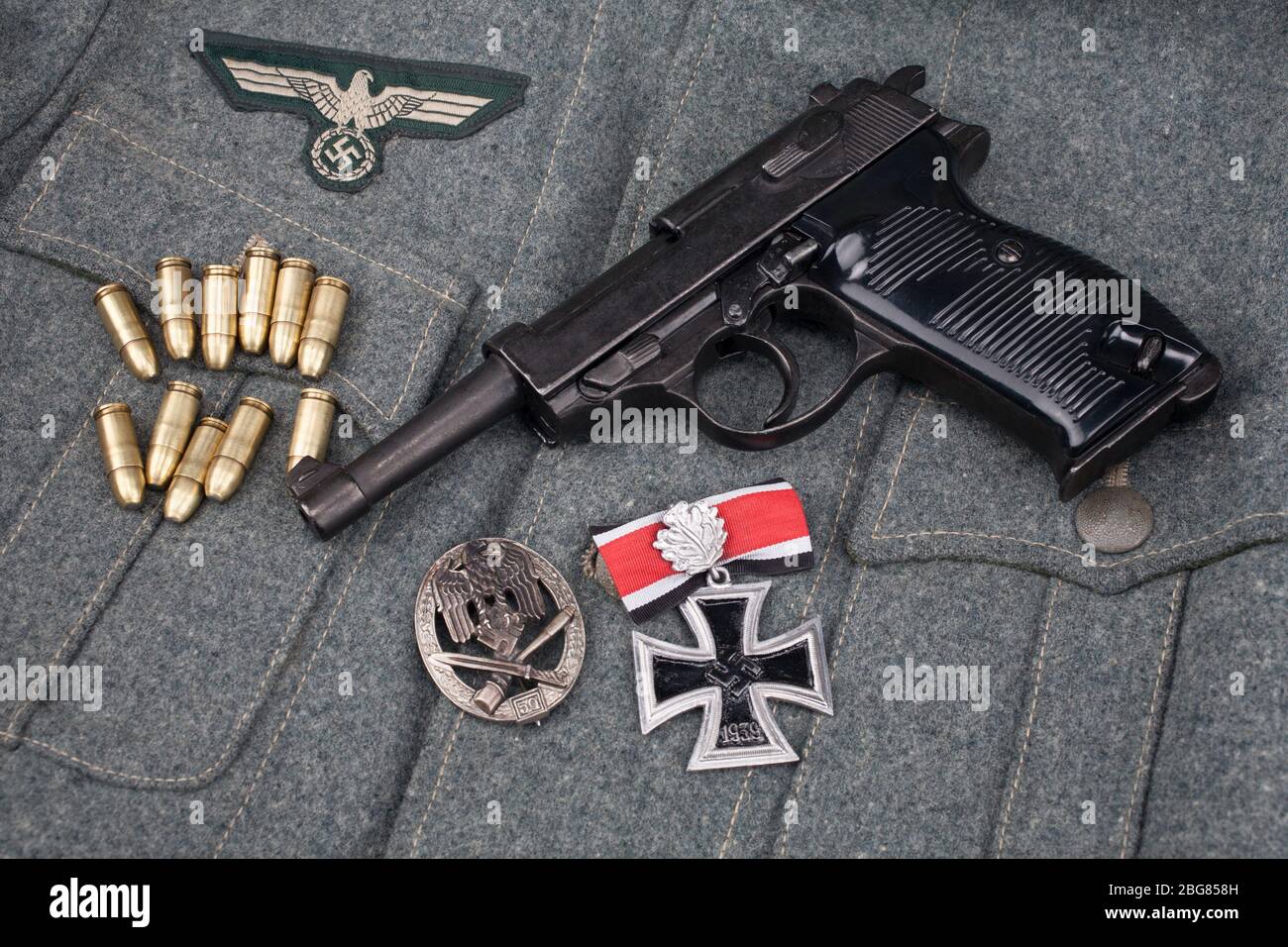 WWII Ära nazi deutsche Armee 9 mm halbautomatische Pistole mit Eisenkreuz Auszeichnung auf Armee grau einheitliche Hintergrund Stockfoto