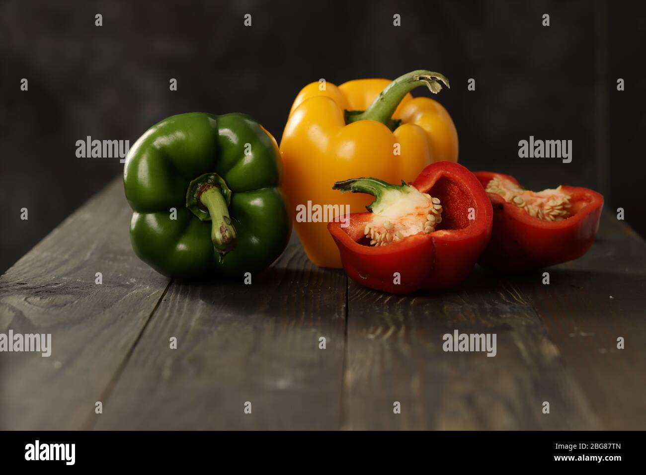 Rote, gelbe und grüne Paprika in einem dunklen und stimmungsvollen Hintergrund Stockfoto
