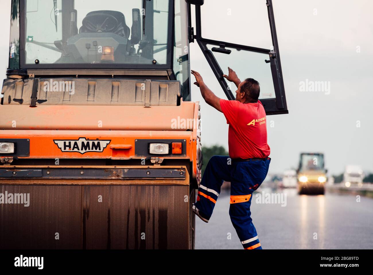 Arbeiter fahren Straßenwalze Auftragen einer neuen Asphaltfläche. Asphalt ebnet Baustelle auf einer Autobahn Stockfoto