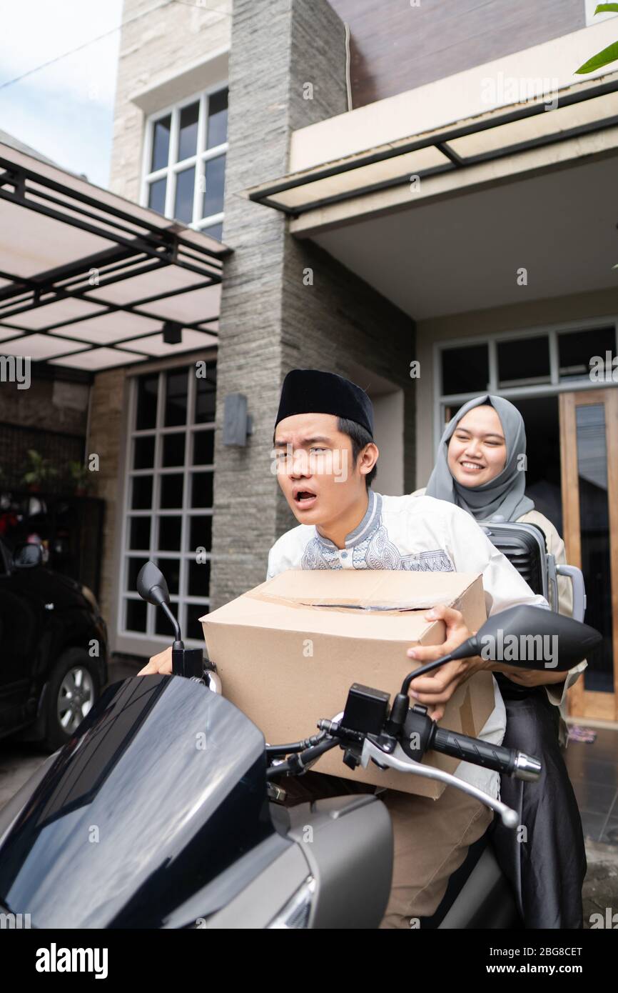 Asiatische muslimische Paare mit Motorrad-Mudik nach Hause gehen und tragen viele Gegenstände, um Eid zu feiern Stockfoto Asiatische muslimische Paare mit Motorrad-Mudik nach Hause gehen und tragen viele Gegenstände, um Eid zu feiern Stockfoto