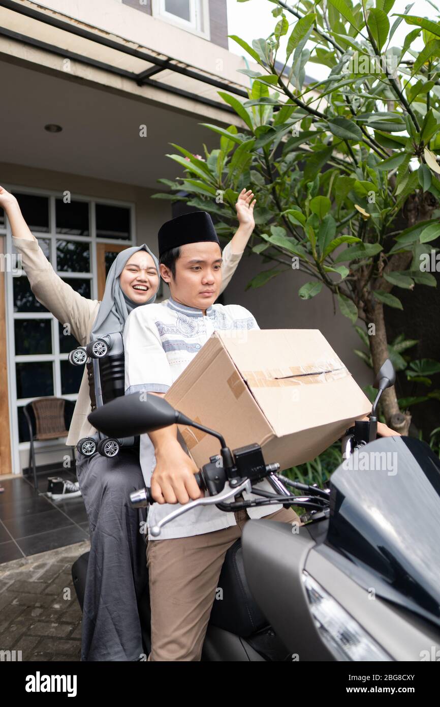 Asiatische muslimische Paare mit Motorrad-Mudik nach Hause gehen und tragen viele Gegenstände, um Eid zu feiern Stockfoto Asiatische muslimische Paare mit Motorrad-Mudik nach Hause gehen und tragen viele Gegenstände, um Eid zu feiern Stockfoto