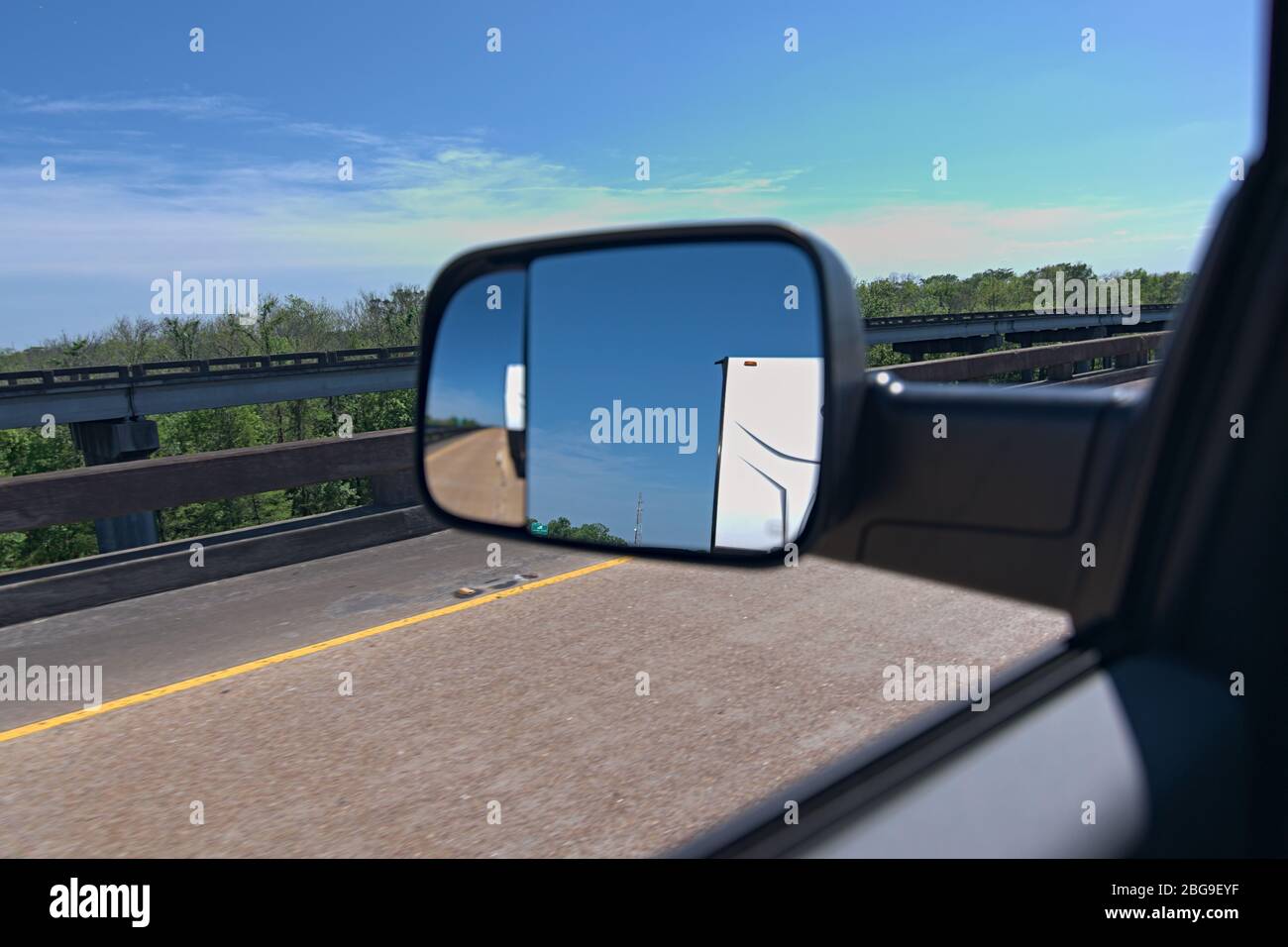 Ansicht des Anhängers vom Seitenspiegel aus. Mit Diesel die Autobahn mit dem Rückspiegel herunterziehen, um den Anhänger hinter sich zu sehen. Stockfoto