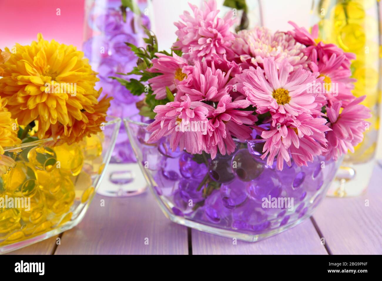 Schöne Blumen in Vasen mit Hydrogel auf dem Tisch aus nächster Nähe Stockfoto
