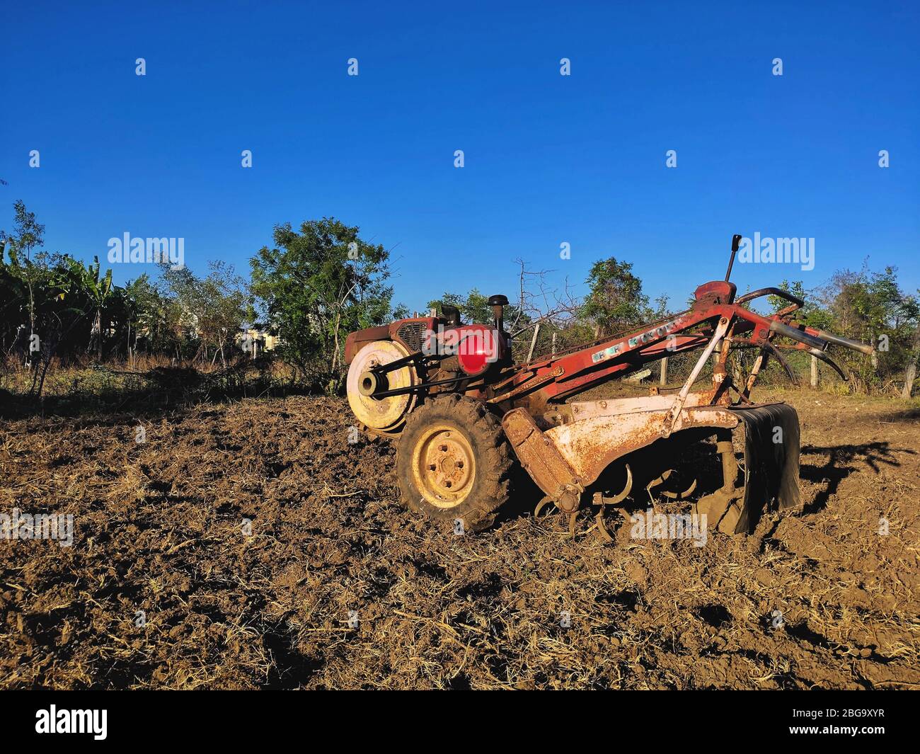 Handfarming Mini Traktor auf landwirtschaftlichen Flächen. Motorkultivator am chennai in der Kategorie. Roter Boden und blauer Himmel. Mini Farm Walking Traktor. Chennai Weit Stockfoto