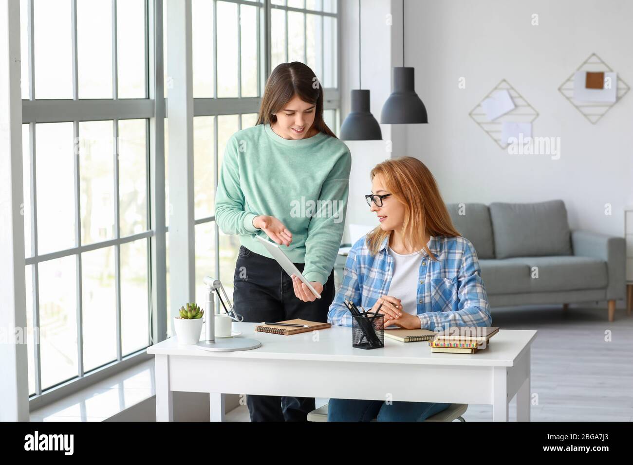 Frau hilft ihrer Mutter beim Online-Lernen zu Hause Stockfoto