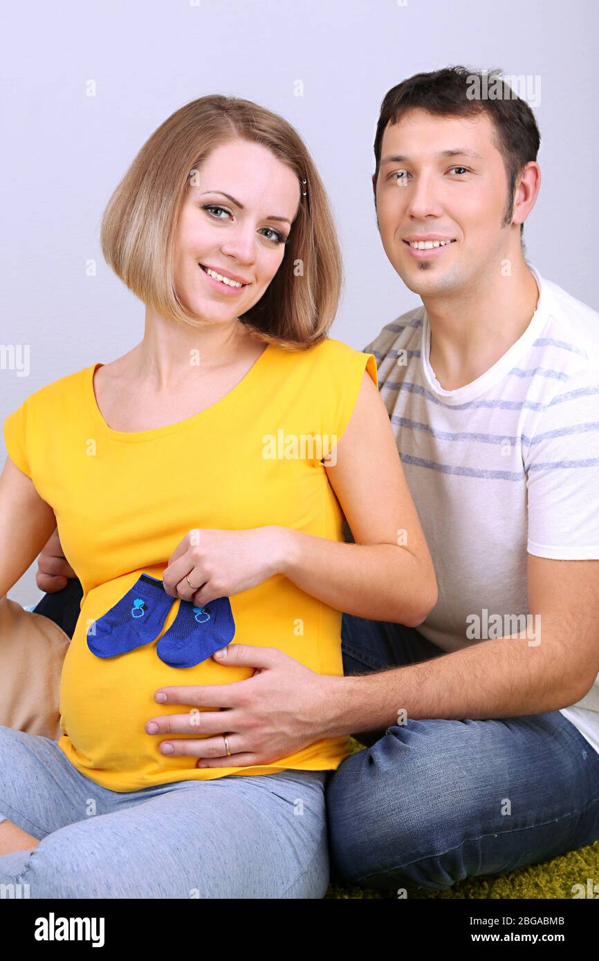 Junge schwangere Frau hält Baby Socken mit ihrem Mann auf dem Boden zu Hause Stockfoto
