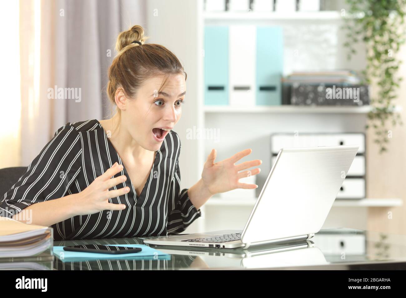 Begeisterte Unternehmerin feiert gute Nachrichten auf dem Laptop auf einem Schreibtisch im Homeoffice Stockfoto